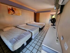 A room with two beds, a small kitchenette, and a ceiling fan. - CASA AMARELA (João Pessoa)