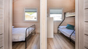 Quarto pequeno com duas beliches, janela, paredes de madeira e teto inclinado.