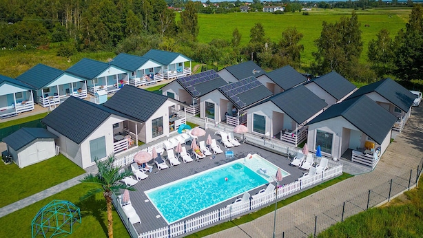 Um conjunto de casas de férias modernas, térreas, com piscina e área de estar compartilhadas.