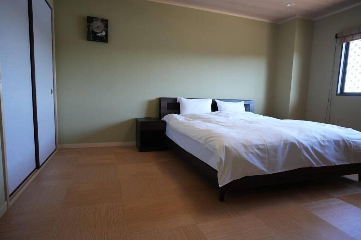 Une chambre à coucher avec un lit, une table de chevet et une fenêtre.