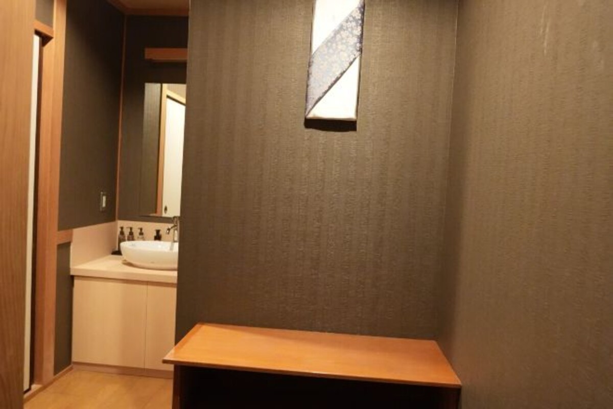 Un baño con tocador de madera, lavamanos y espejo.
