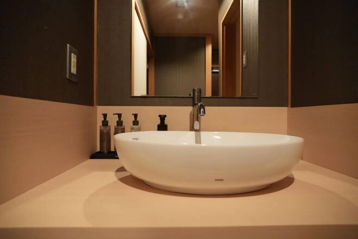 Une salle de bain avec un lavabo blanc, un miroir et des articles de toilette posés sur le comptoir.