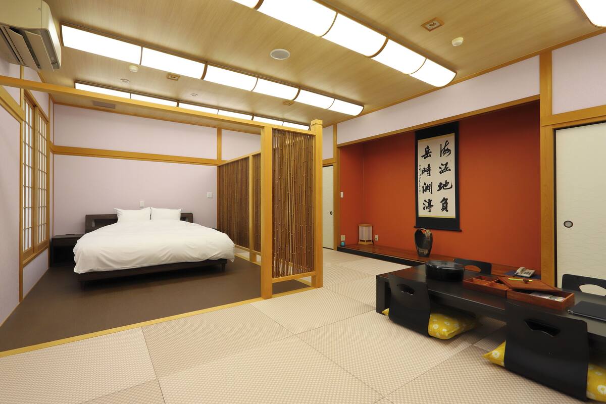 Une pièce de style japonais traditionnel, avec un sol recouvert de tatamis, un lit, un bureau en bois et un paravent en papier.