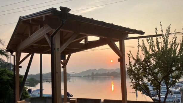 Puinen terassi, jossa on pergola, pieni uima-allas ja näkymä auringonlaskulle vesistön yllä.