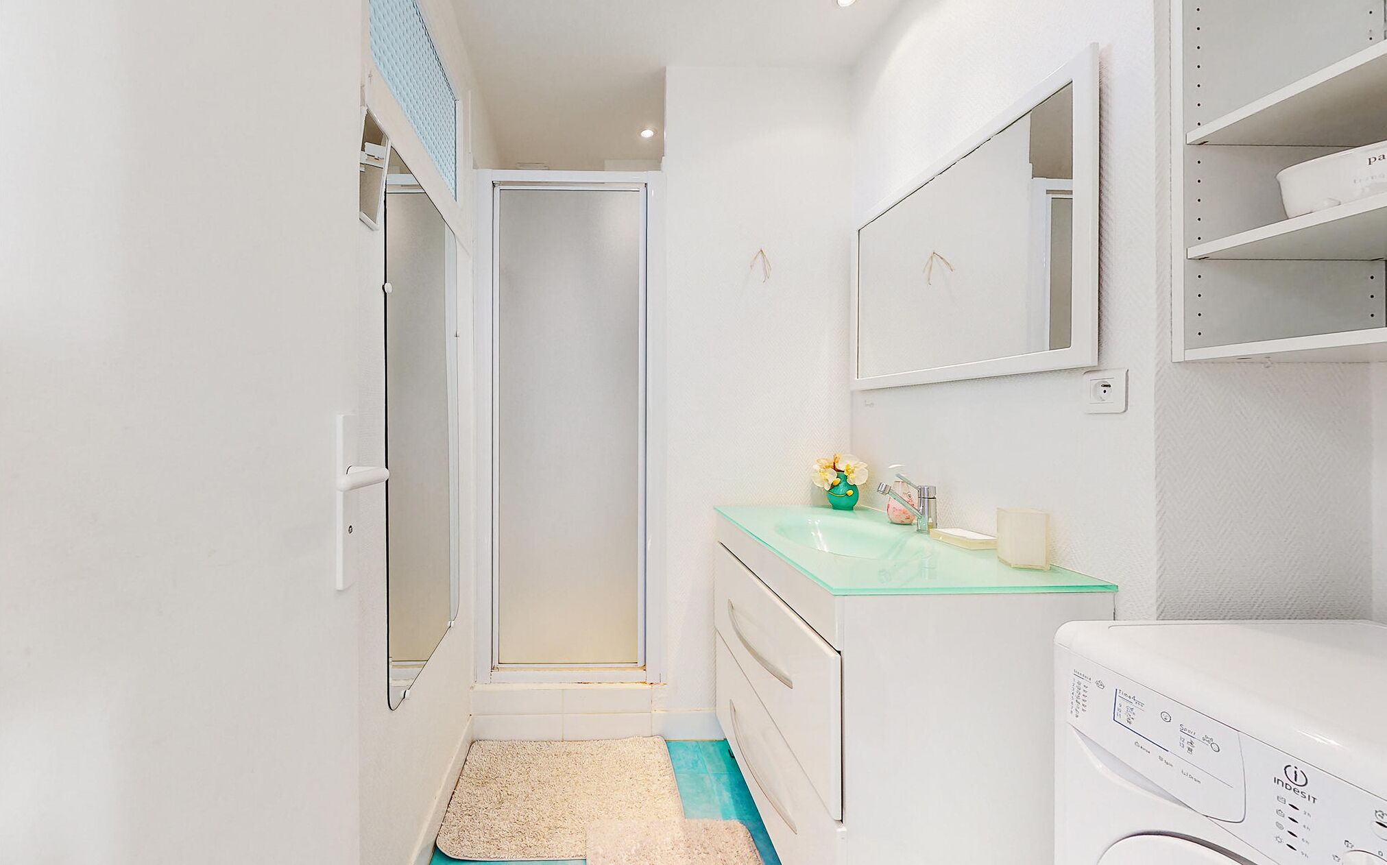 A compact bathroom with a glass sink, a toilet, and a washing machine.