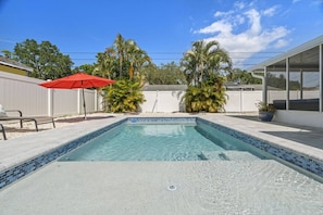 A rectangular swimming pool with a tiled edge, surrounded by a concrete deck.