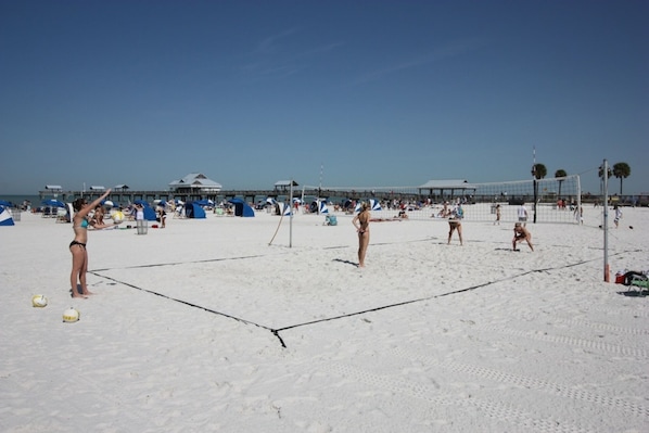 A beach volleyball court with players and spectators.