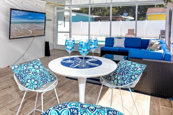 A covered outdoor seating area with a table, chairs, and a sofa.
