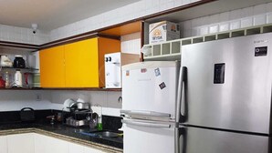 A compact kitchen with white cabinets, a stainless steel refrigerator, a microwave, and a coffee maker. - Casa Amarela Aeroclube (Aeroclube João Pessoa)