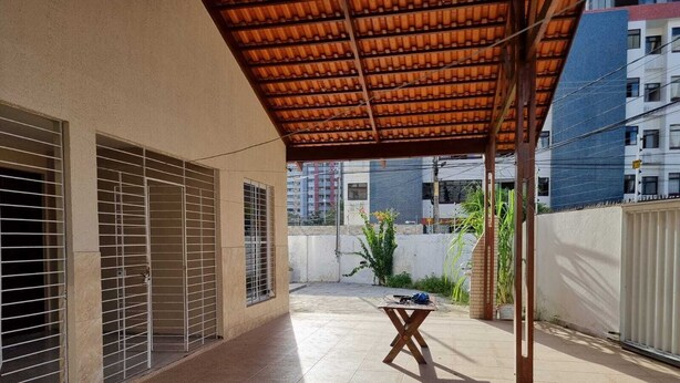A covered outdoor area with tiled flooring, metal gates, and a table with items on it. - Casa Amarela Aeroclube (Aeroclube João Pessoa)