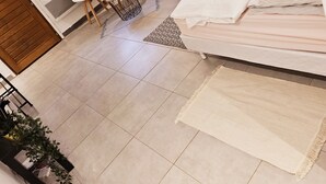 Un dormitorio moderno con una cama, un escritorio y una silla. Hay una ventana con cortinas, una planta y una mesita redonda.