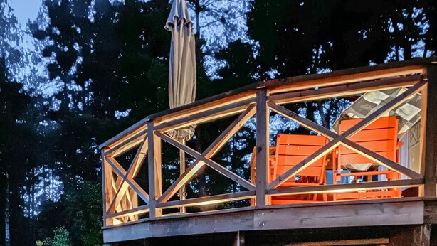 Een houten dek met glazen omheining, gedragen door een metalen constructie.