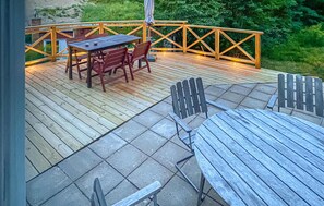 Een houten terras met een tafel en stoelen, omringd door een reling.