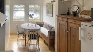 Een gezellige keuken met een houten bankje, een ronde tafel en een koelkast.