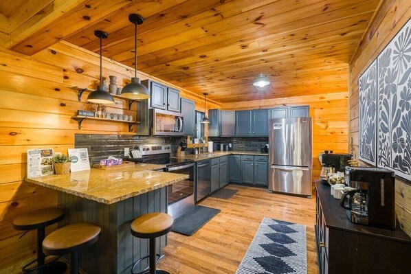 Interior de una cabaña de madera con cocina, taburetes de bar y un refrigerador.