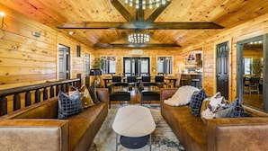A log cabin interior with a central seating area, wooden walls, and a chandelier.