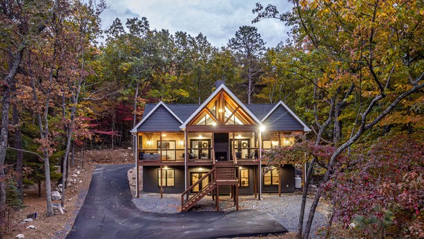 A two-story log cabin with a deck and a staircase leading to the upper level.