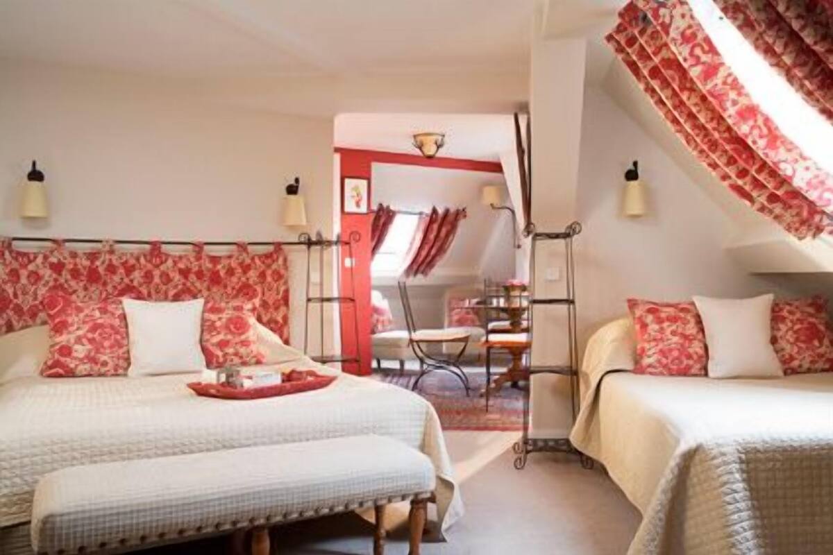 A bedroom with two beds, a small table, and a chair.