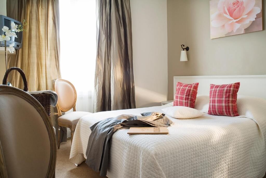 Une chambre d’hôtel avec un lit, une chaise, un bureau et des rideaux.