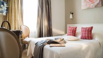 Une chambre d’hôtel avec un lit, une chaise, un bureau et des rideaux.