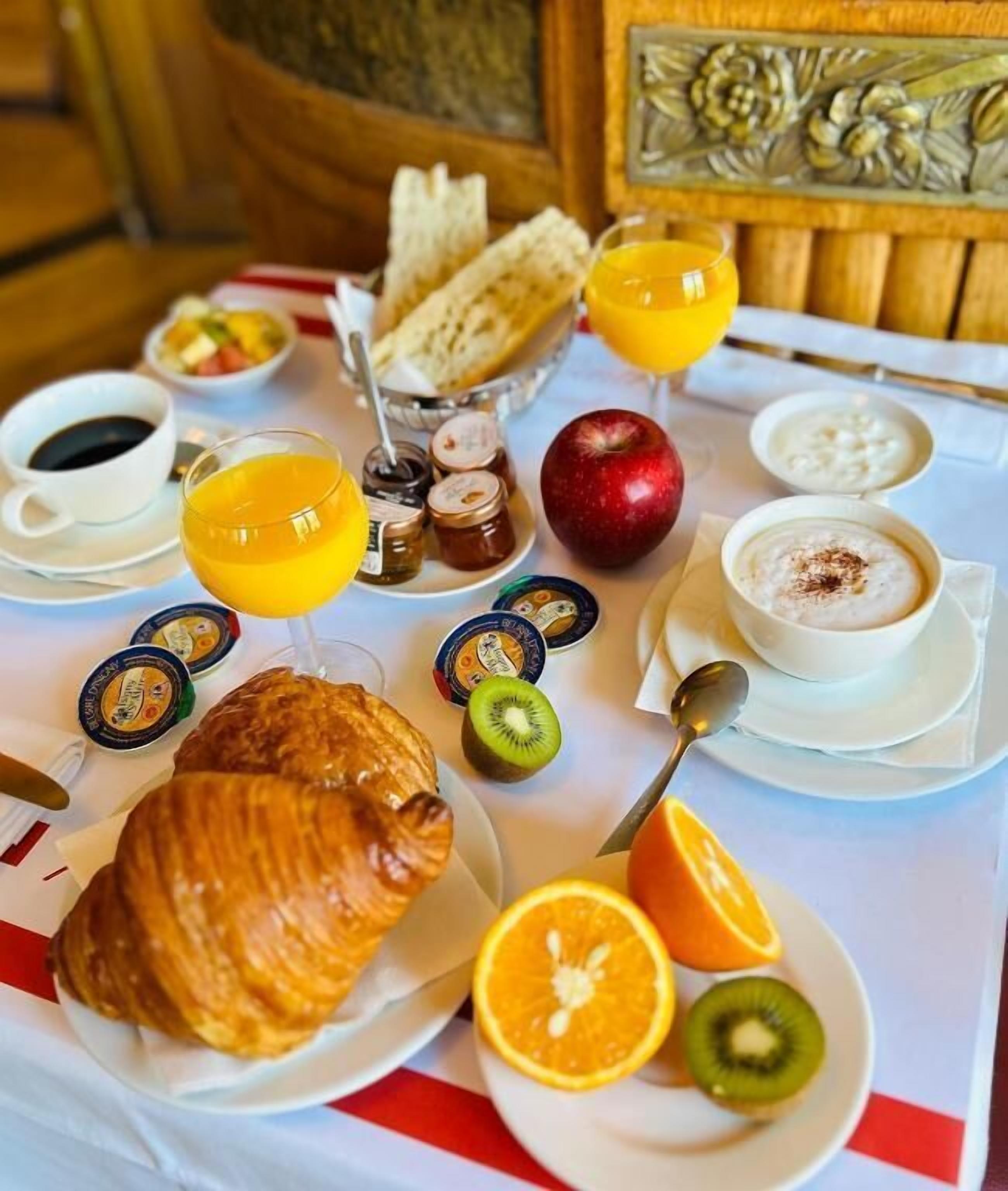 Een ontbijttafel met croissants, fruit, koffie en sap.