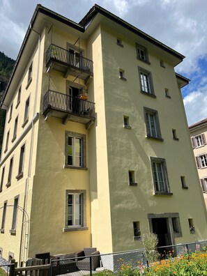 Un edificio de varios pisos con balcones, ventanas y una entrada visible.