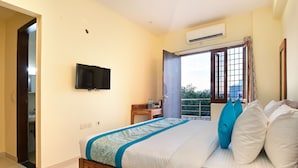 A bedroom with a bed, a TV, a window, and a door leading to a balcony. - Hotel The York (Noida)
