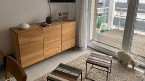 Een moderne woonkamer met een houten kast, een flatscreen televisie, een afstandsbediening en ingelijste foto's.