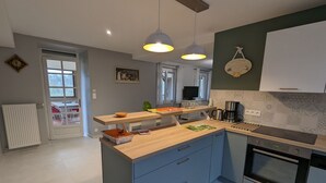 A modern kitchen with a central island, pendant lights, and a built-in oven.