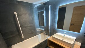Une salle de bain moderne avec une douche à parois de verre, une baignoire blanche et un meuble-lavabo en bois.