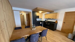 Une cuisine compacte avec des meubles de rangement en bois, une table à manger avec des chaises et un four visible.