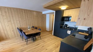 Une cuisine compacte équipée d’un four à micro-ondes, d’un grille-pain et d’un évier. On y trouve une table à manger avec des chaises et un plancher en bois.