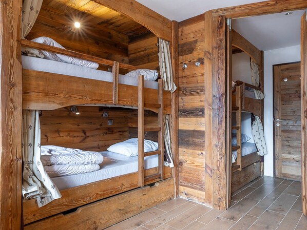 A wooden bunk bed room with a door and a small window.