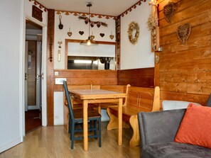 A cozy room with a wooden dining table and chairs, a sofa, and a wooden wall with heart-shaped decorations.
