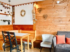 A cozy room with wooden walls, a dining table with chairs, a sofa, and decorative heart-shaped wall hangings.