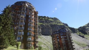 Un hôtel à plusieurs étages, doté de balcons, situé dans un cadre montagneux.