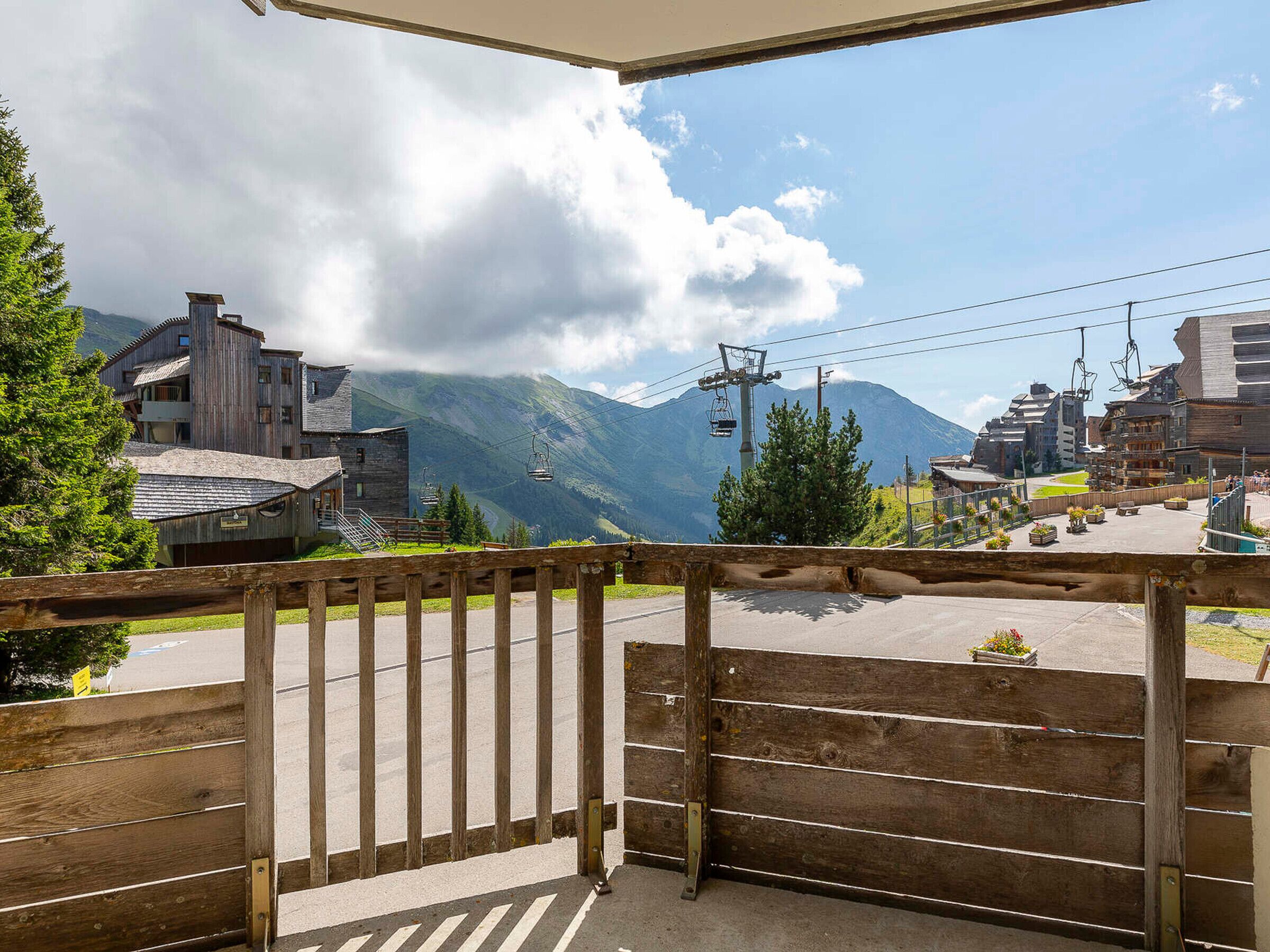 A wooden balcony with a view of a mountain and a ski lift.