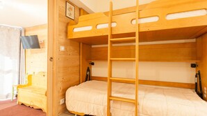 A bunk bed room with wooden walls and a small desk.