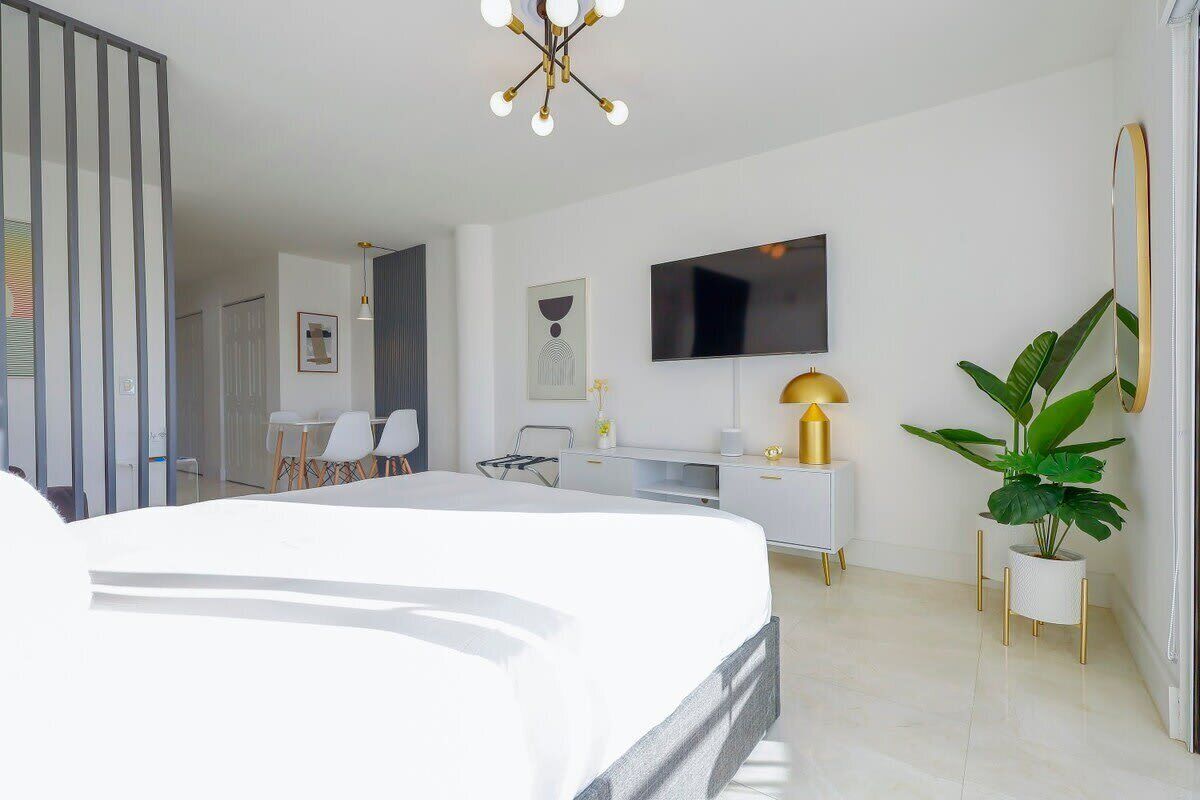 Une chambre d’hôtel moderne, dotée d’un grand lit, d’un bureau, d’une chaise, d’une télévision et d’une plante en pot.