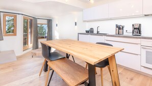 Una cocina moderna con armarios blancos, una mesa de comedor de madera y un horno empotrado.