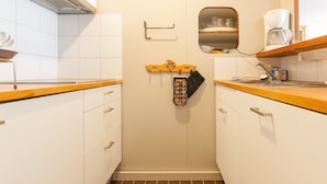 A compact kitchen with white cabinets, a wooden countertop, a built-in oven, and a small window above the sink.