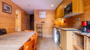 A wooden interior with a kitchen, dining area, and a clock on the wall.
