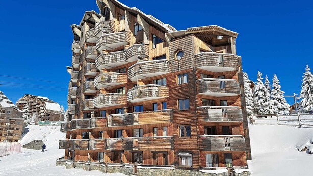 A multi-story wooden building with balconies, set in a snowy environment.