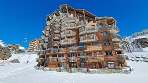 A multi-story hotel with wooden exterior and balconies, located in a snowy mountainous area.