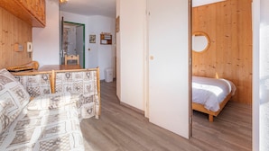 A cozy room with a wooden bed, a small desk, and a sofa. There is a door leading to another room.