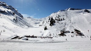 Ett snötäckt berglandskap med en skidlift, en skidbacke och en klarblå himmel.