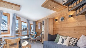 A cozy room with a wooden ceiling, a sofa with decorative pillows, a dining table with chairs, and a view of snowy mountains through large windows. - Modern duplex 2/3 rooms, 6 ppl, sheets incl, Avoriaz (Avoriaz)