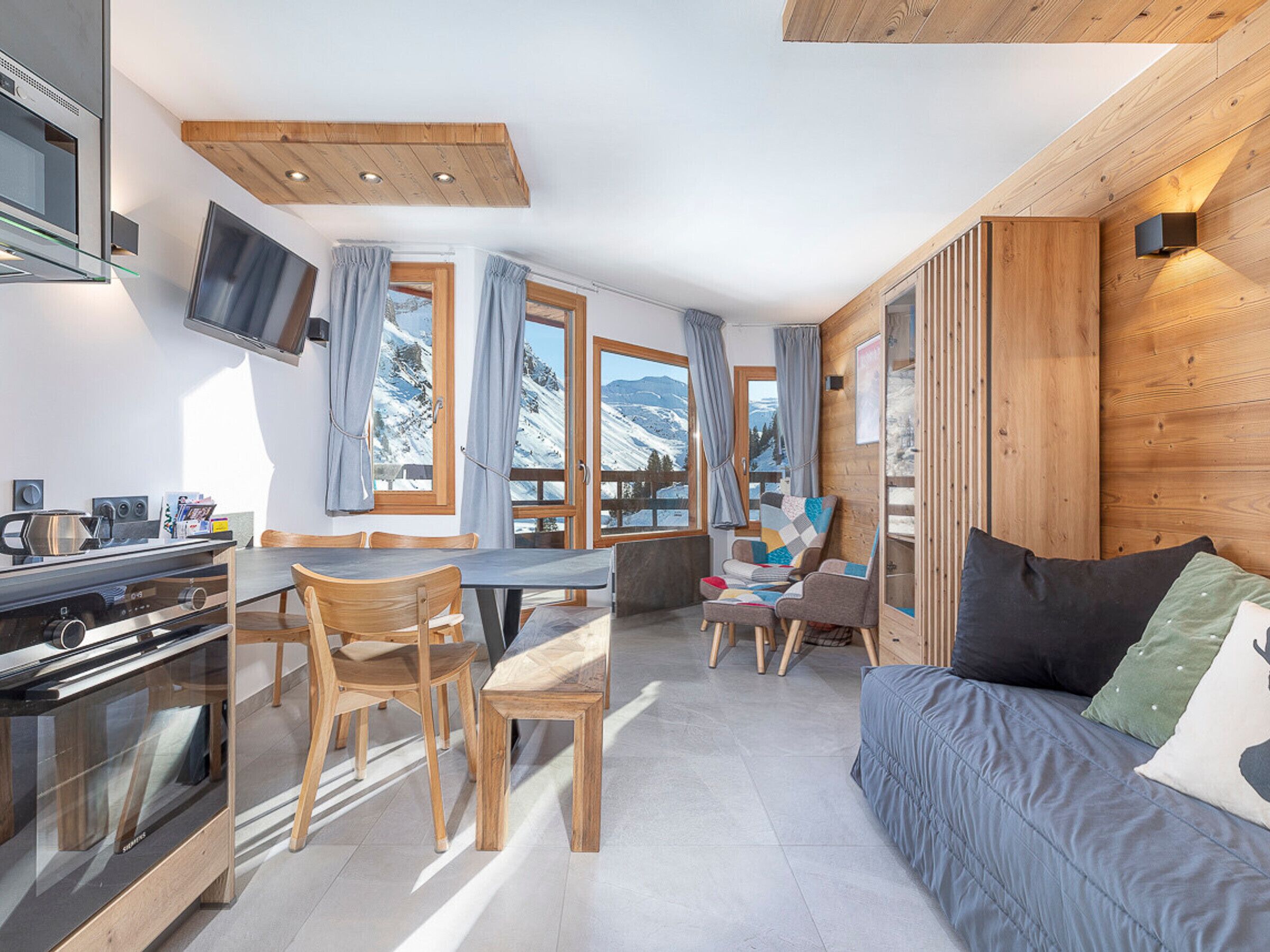 A modern kitchen with a built-in oven and a dining area with wooden chairs and a table.