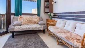 Une chambre confortable avec un lit, un canapé, une table de chevet en bois et une fenêtre avec des rideaux.