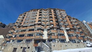 Un hôtel à plusieurs étages, doté de balcons, d’une façade en pierre et surplombant un ciel d’un bleu limpide.